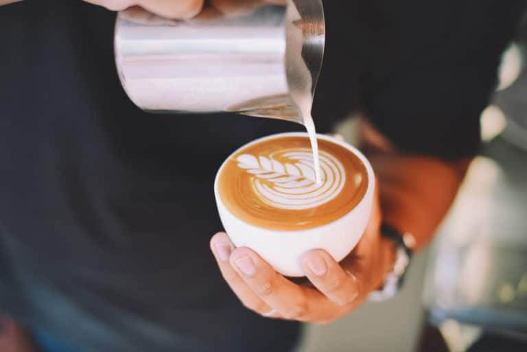 Lifestyle photo of a barista pouring a latte