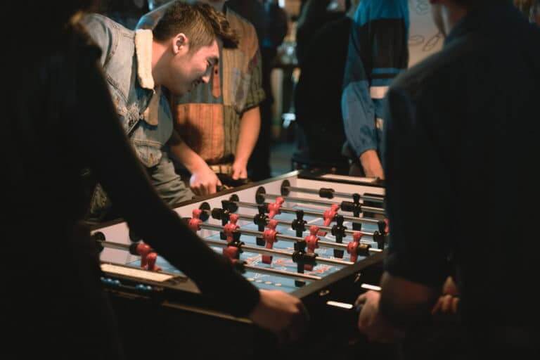 Lifestyle photo of a group of friends playing foosball