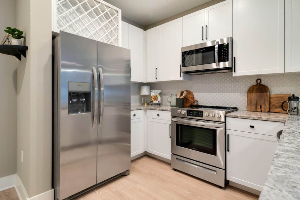 Modern stainless steel appliances and wine rack above fridge in apartment homes at Margaux Midtown