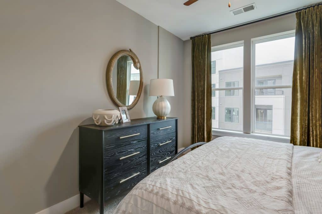 Dresser next to large bedroom windows in apartment home at Margaux Midtown