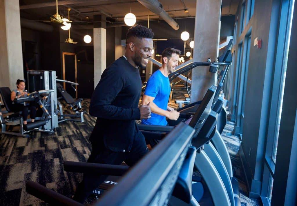 Two men running on treadmills in Margaux Midtown's fitness center